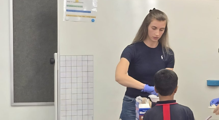 Stephanie serving a student a cup of food at a nutrition workshop